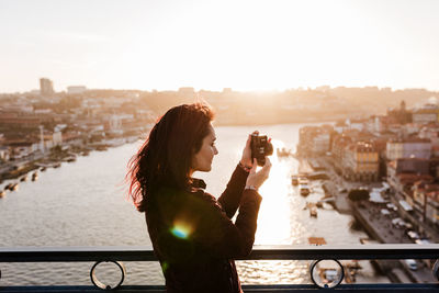 Woman in porto bridge taking pictures with camera at sunset. tourism in city europe. travel