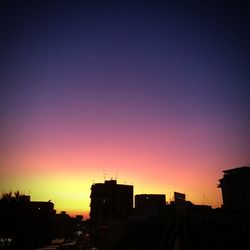 Silhouette cityscape against sky at dusk