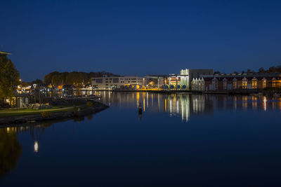 Reflection of illuminated buildings in lake against blue sky