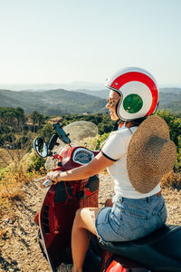 People sitting on motorcycle against sky