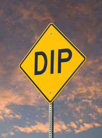 Low angle view of road sign against sky during sunset