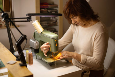 Woman sewing fabric with a vintage, retro sewing machine. fashion, creation and tailoring. 