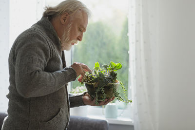 Mature man taking care of house plants