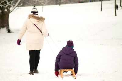 Rear view of people walking on snow covered landscape