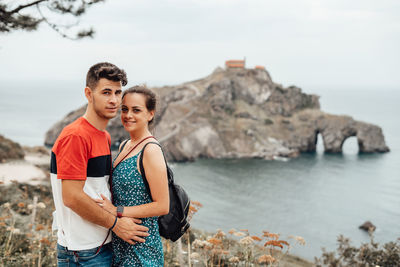 Portrait of couple embracing while standing by sea