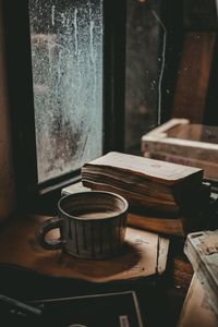 Close-up of coffee cup by window on table