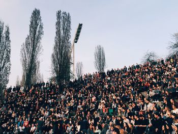 Crowd on grassy field against sky at mauerpark