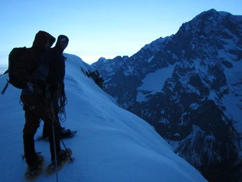 People standing on snowcapped mountain against clear sky