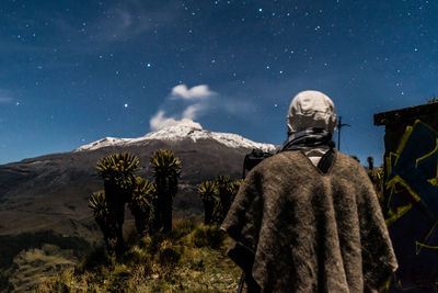 Rear view of man standing in desert against star field