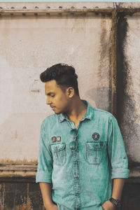 Full length of young man looking away against wall