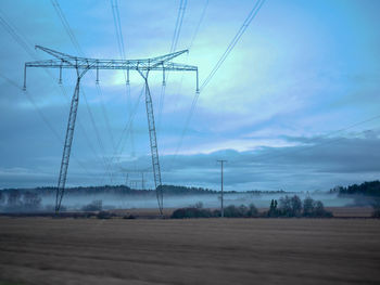 Low angle view of electricity pylon on field against sky