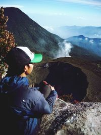 Man looking at view while sitting on mountain