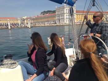 People sitting on boat in city against sky