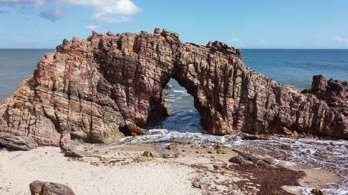 Rock formation on beach against sky