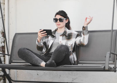 A young beautiful caucasian girl holds a smartphone in her hand and learns meditation online