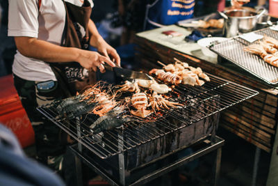 Midsection of woman preparing food on barbecue grill