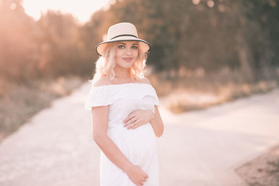 Pregnant woman with hat standing at park