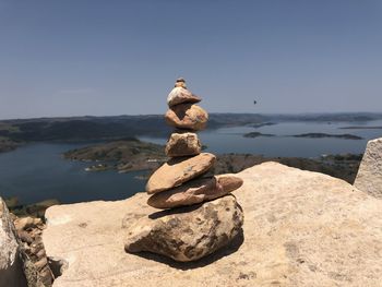 Stack of stones on shore against sky