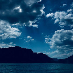 Scenic view of sea and mountains against blue sky