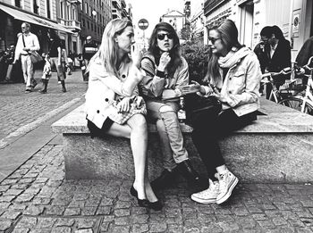 Young woman sitting on sidewalk in city
