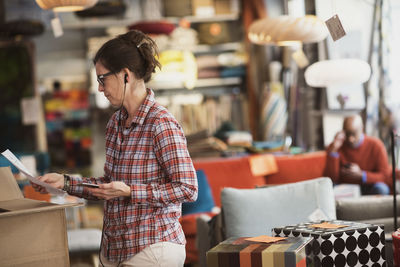 Owner listening music through phone while reading document at store