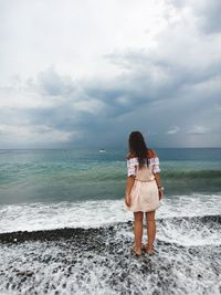 Woman standing on beach against sky