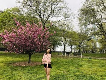 Portrait of smiling young woman standing against pink flowering tree