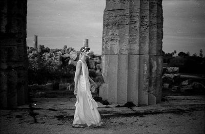 Woman standing by statue against tree