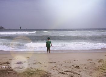 Rear view of boy standing on shore