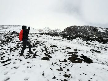 Man standing on snow covered landscape against sky