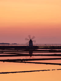 Silhouette cranes against sky during sunset