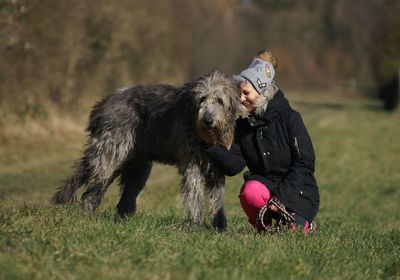 Woman crouching with dog on field