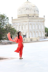 Full length of woman with umbrella against building in city