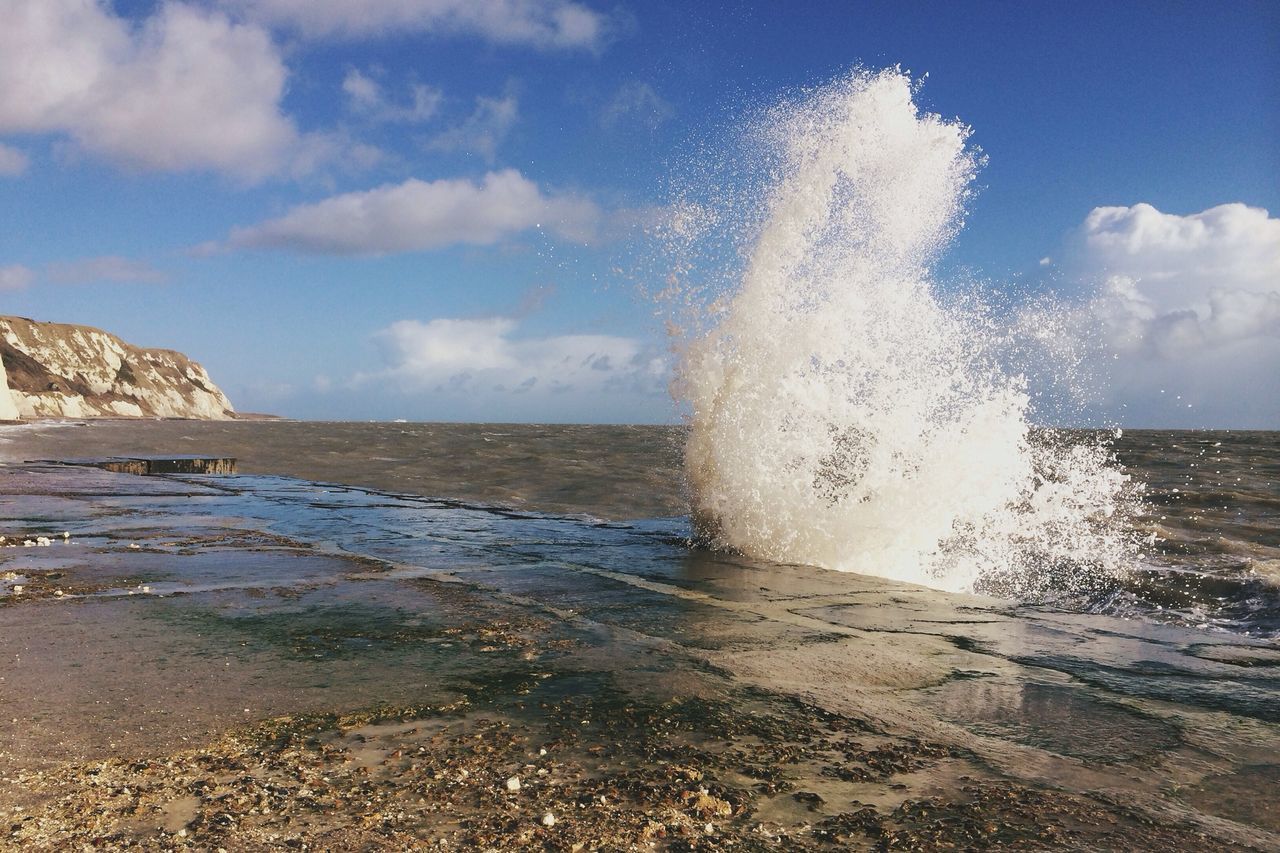 water, sea, sky, beach, scenics, beauty in nature, shore, wave, horizon over water, motion, nature, tranquil scene, tranquility, surf, splashing, cloud - sky, sand, sunlight, rock - object, idyllic