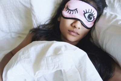 High angle view of woman wearing eye mask while sleeping in bed