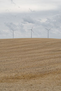 Wind turbines on field against sky