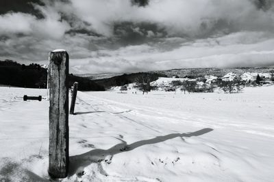 Snow covered field against cloudy sky