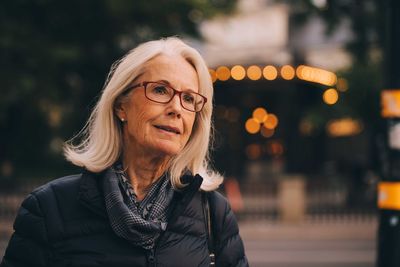 Senior woman looking away while standing in city