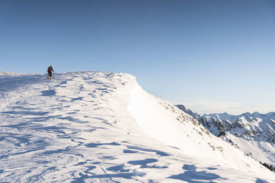 Rear view of person on snowcapped mountain against sky