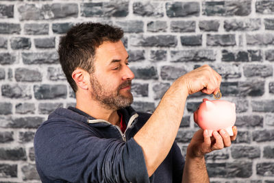 Man holding ice cream against wall