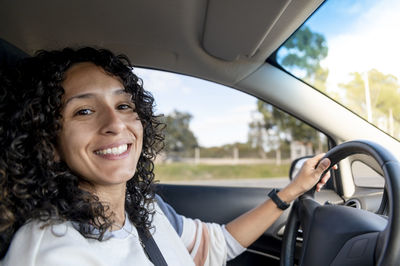 Happy woman smiling while driving a car on the road.