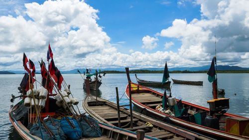 Fishing boats moored in sea against sky