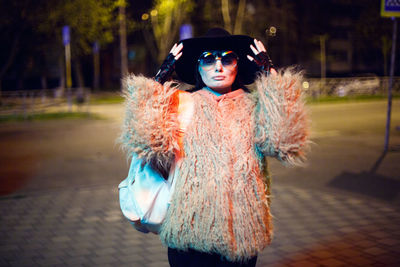 Portrait of woman wearing hat standing on street in city