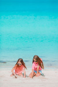 Sisters plying with sand on beach