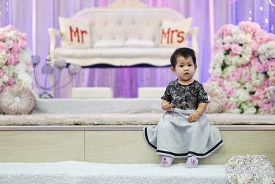 Portrait of cute girl sitting on stage during wedding ceremony