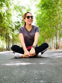 Woman wearing sunglasses while sitting on footpath at park