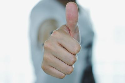 Midsection of man showing thumbs up