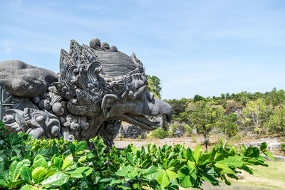 Statue against trees and plants against sky