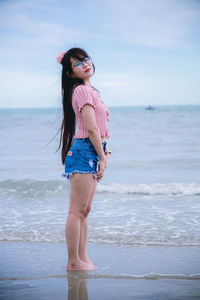 Full length of young woman standing on beach