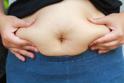 Midsection of pregnant woman touching abdomen
